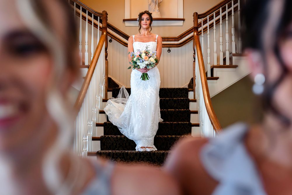 A bride stands gracefully on a staircase holding a bouquet.