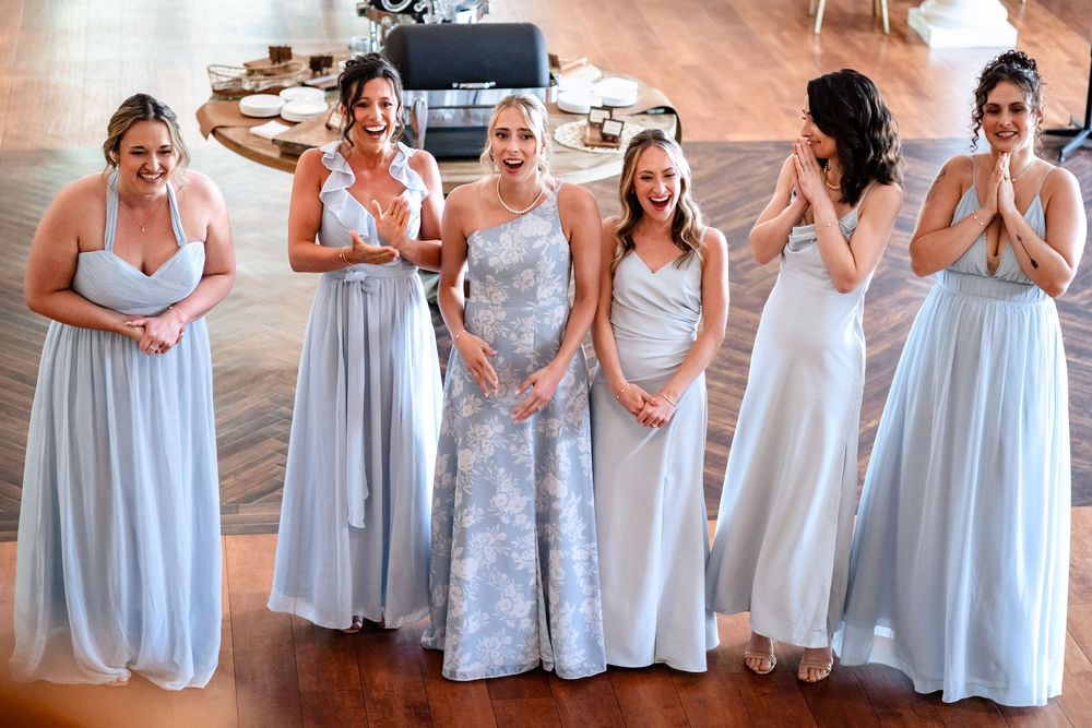 A group in light blue bridesmaid dresses poses together during a wedding celebration.
