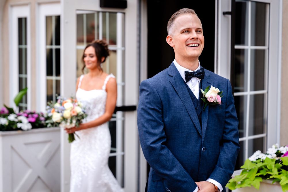 A romantic moment captured between a couple in formal attire outside a white building with French doors.