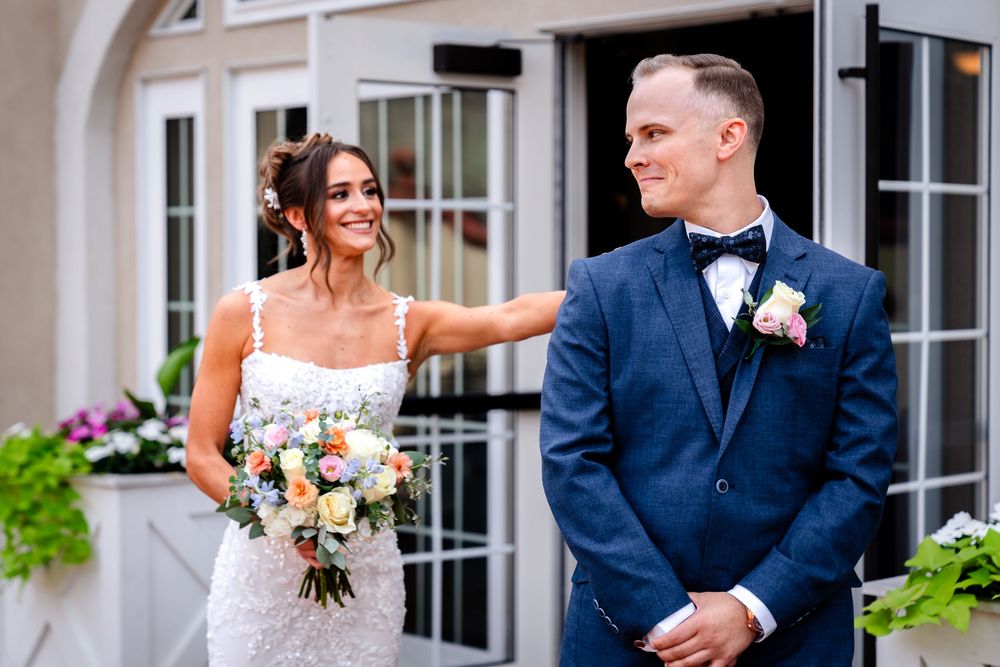 Wedding couple shares a joyful moment in front of an elegant building exterior.