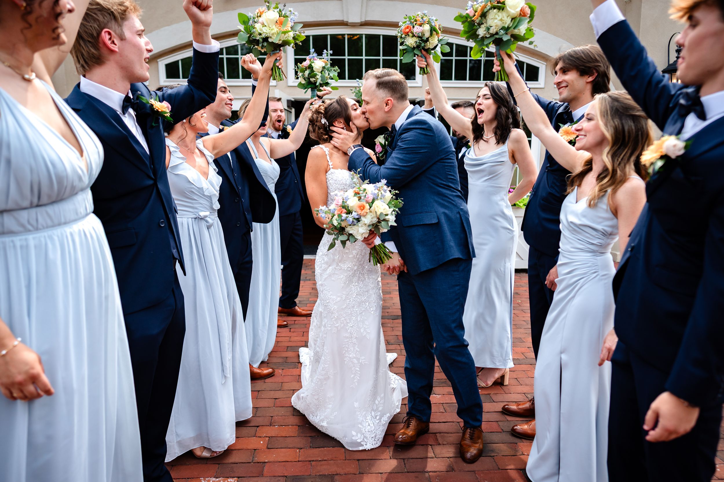 Joyful wedding party celebrates with raised arms in an outdoor celebration.