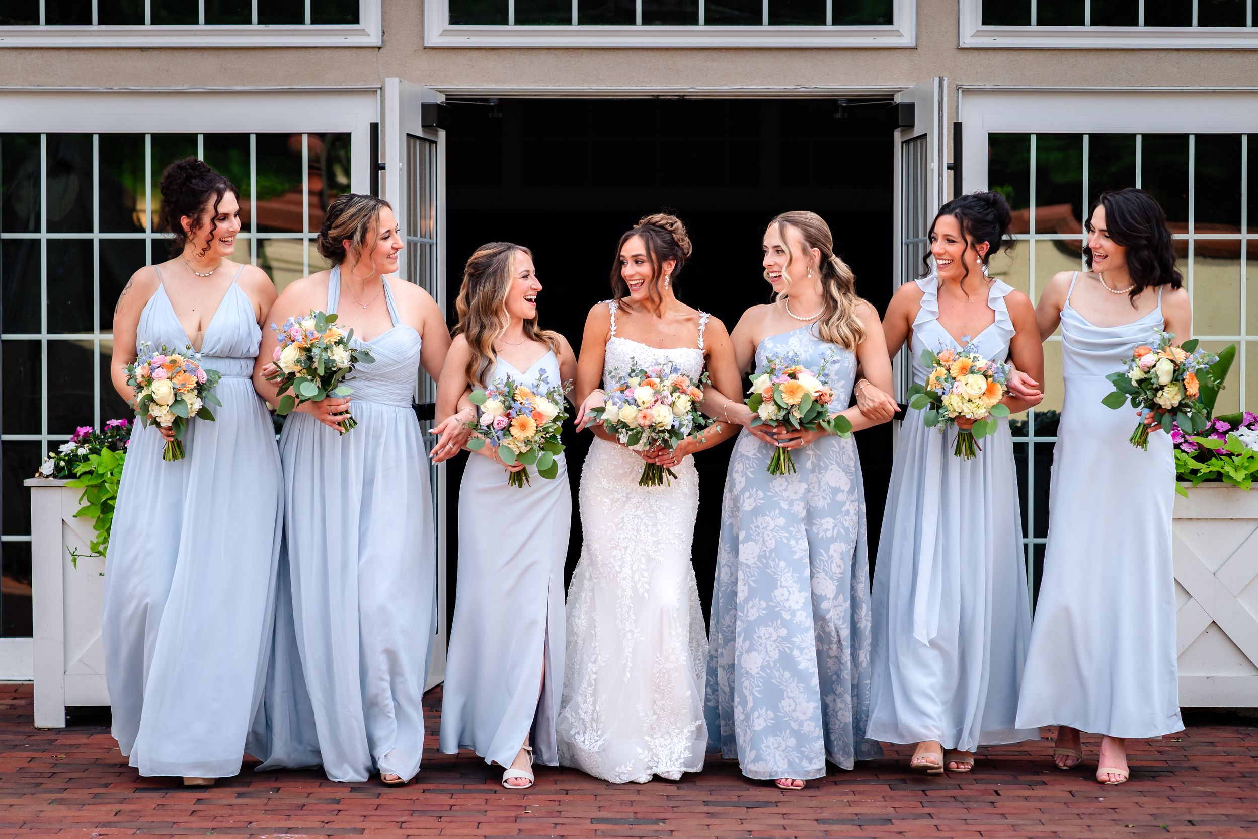 Bridesmaids in light blue dresses pose with bride for outdoor wedding photos.