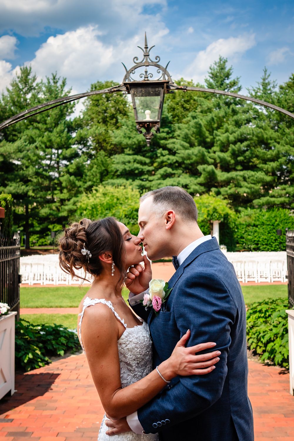 Intimate wedding moment captured on brick patio with greenery backdrop.