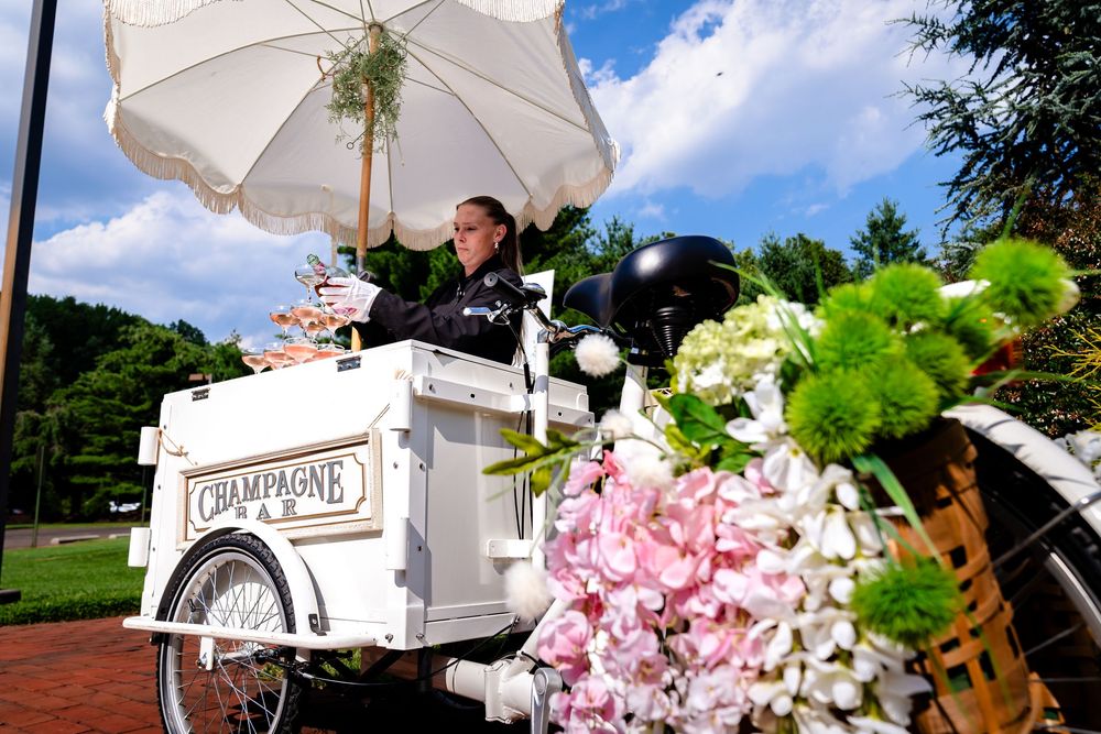 Elegant wedding decor featuring white umbrellas and pink floral arrangements under blue skies.