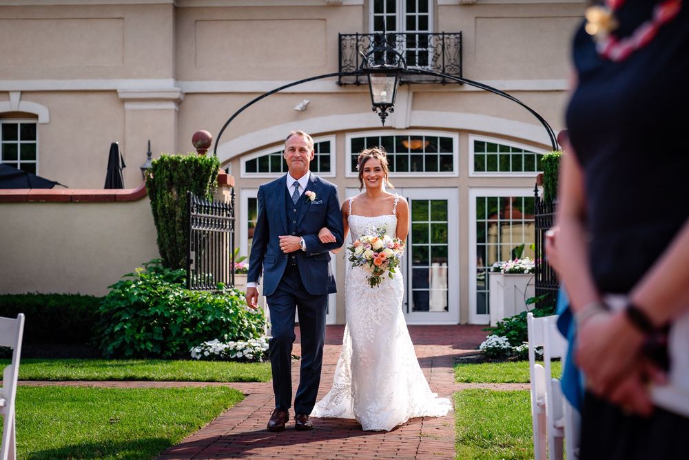 Wedding party poses outside an elegant venue with French doors and classic architecture.