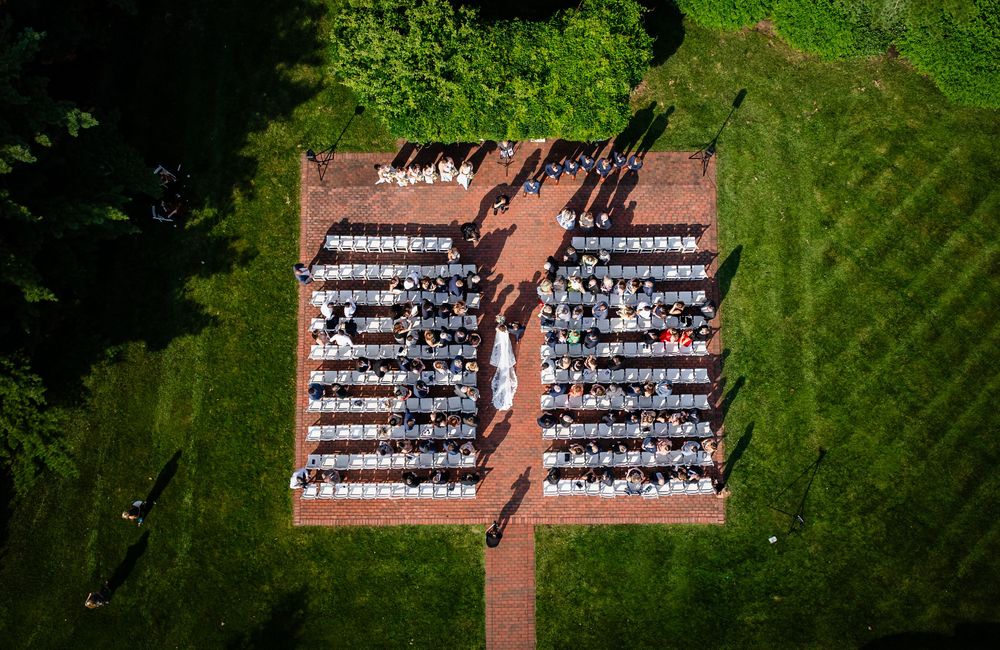 Aerial view of wedding ceremony seating arrangement on a lush green lawn.
