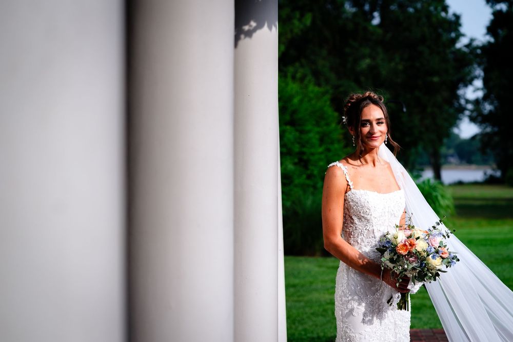 Dramatic wedding portrait with white columns framing the scene in an outdoor garden setting.