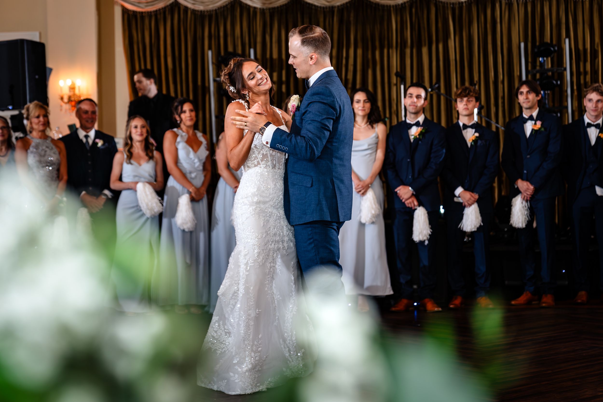 Reception guests dance and celebrate during an indoor wedding party with dramatic lighting.