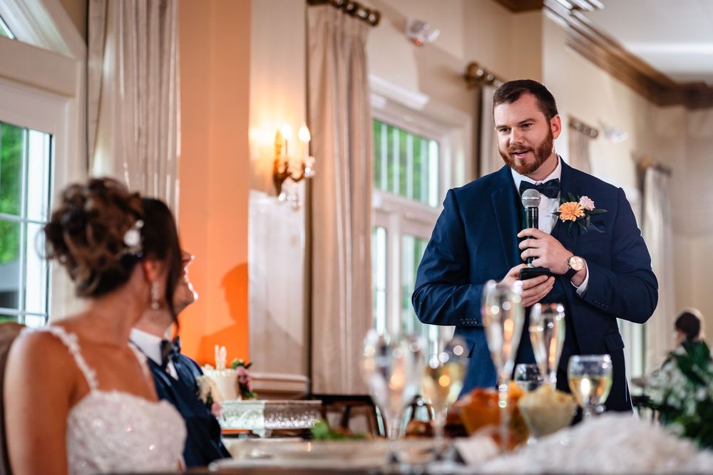 Wedding couple shares joyful moments during reception toasts in an elegantly lit banquet room.