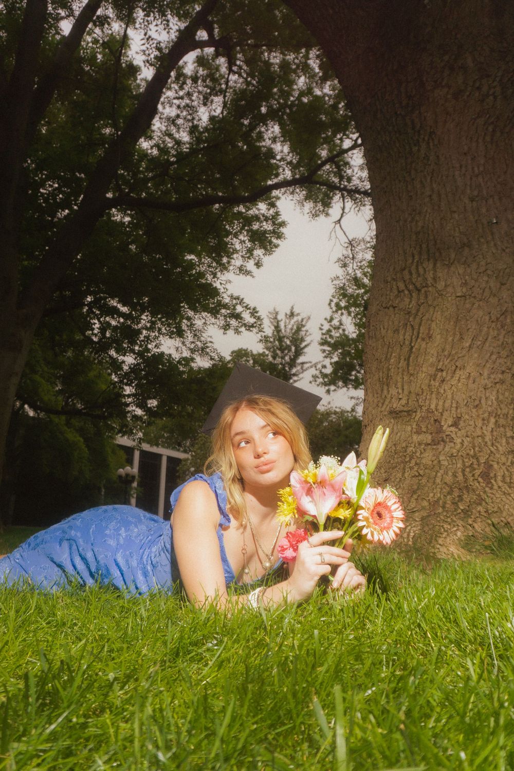 Dreamy garden scene with person resting on grass holding fresh cut flowers.