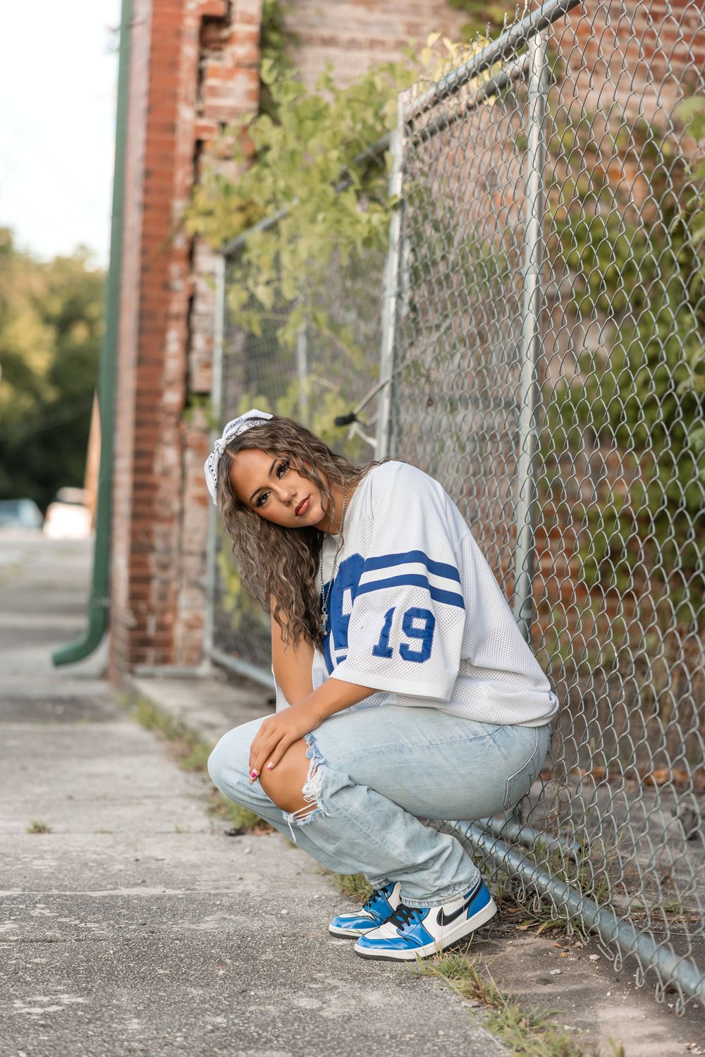 A person in a white jersey and jeans crouches against a chain link fence, shown in a multi-photo sequence.