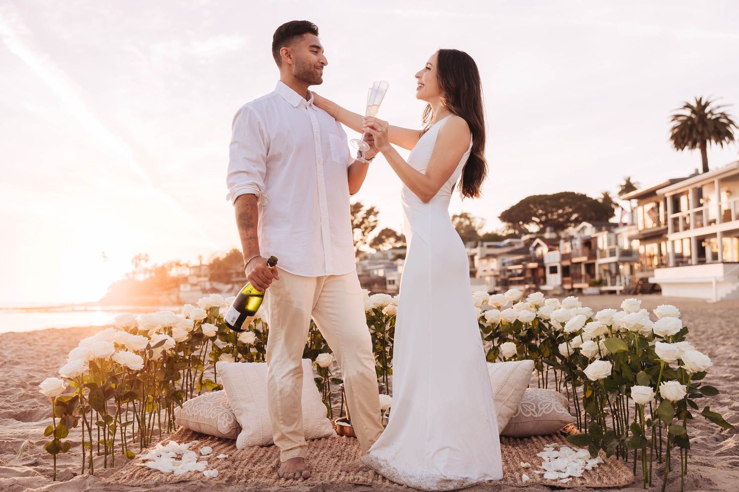 A romantic couple just finished a surprise proposal on Ellwood Bluffa with Ellwood Beach in background at sunset with golden light.