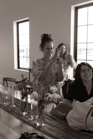 A group celebrates at a dining table with candles and decor in black and white tones.