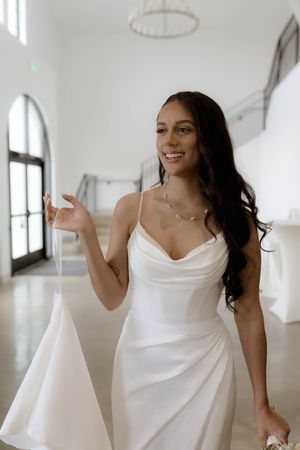 A person in a white wedding dress dances and twirls in a bright modern space.