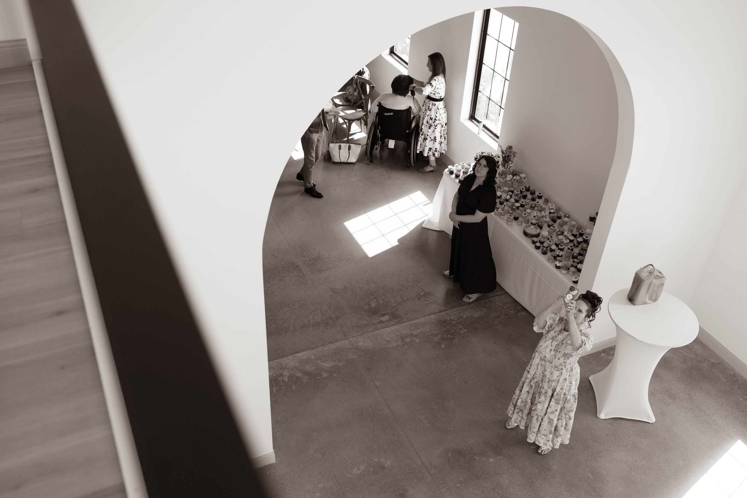 Black and white photo of wedding preparations through an arched doorway.