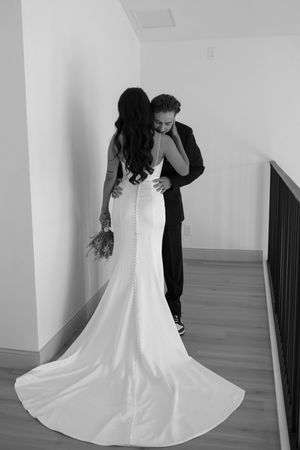 A black and white portrait of a couple in wedding attire sharing an intimate moment.