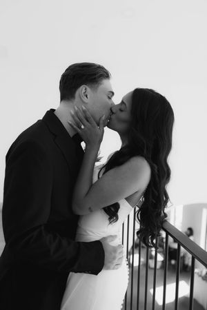 Black and white staircase photoshoot capturing tender moments between newlyweds.