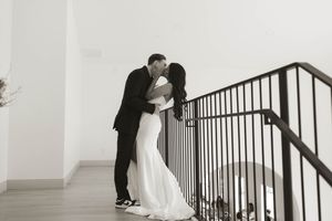 Artistic black and white wedding photos showing a couple's playful interaction on a staircase.