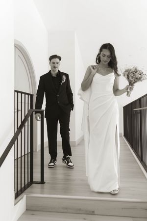 Wedding couple walking up white stairs in black and white photography sequence.