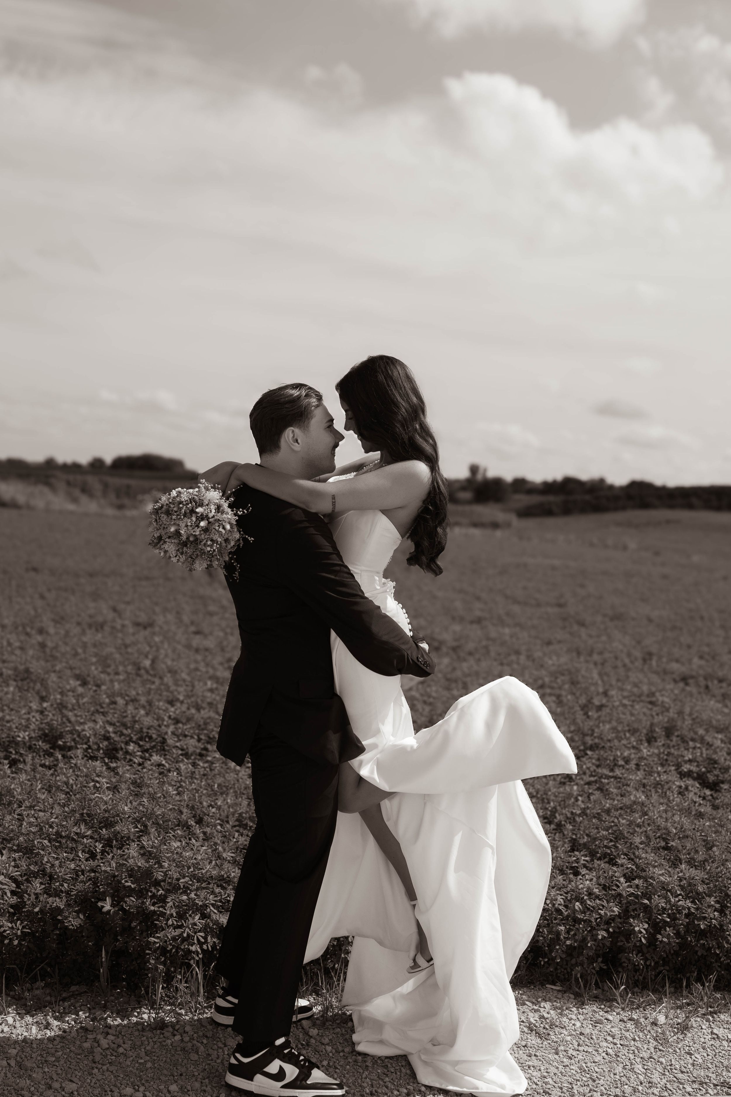 Black and white countryside wedding photos showing romantic moments in an open field.