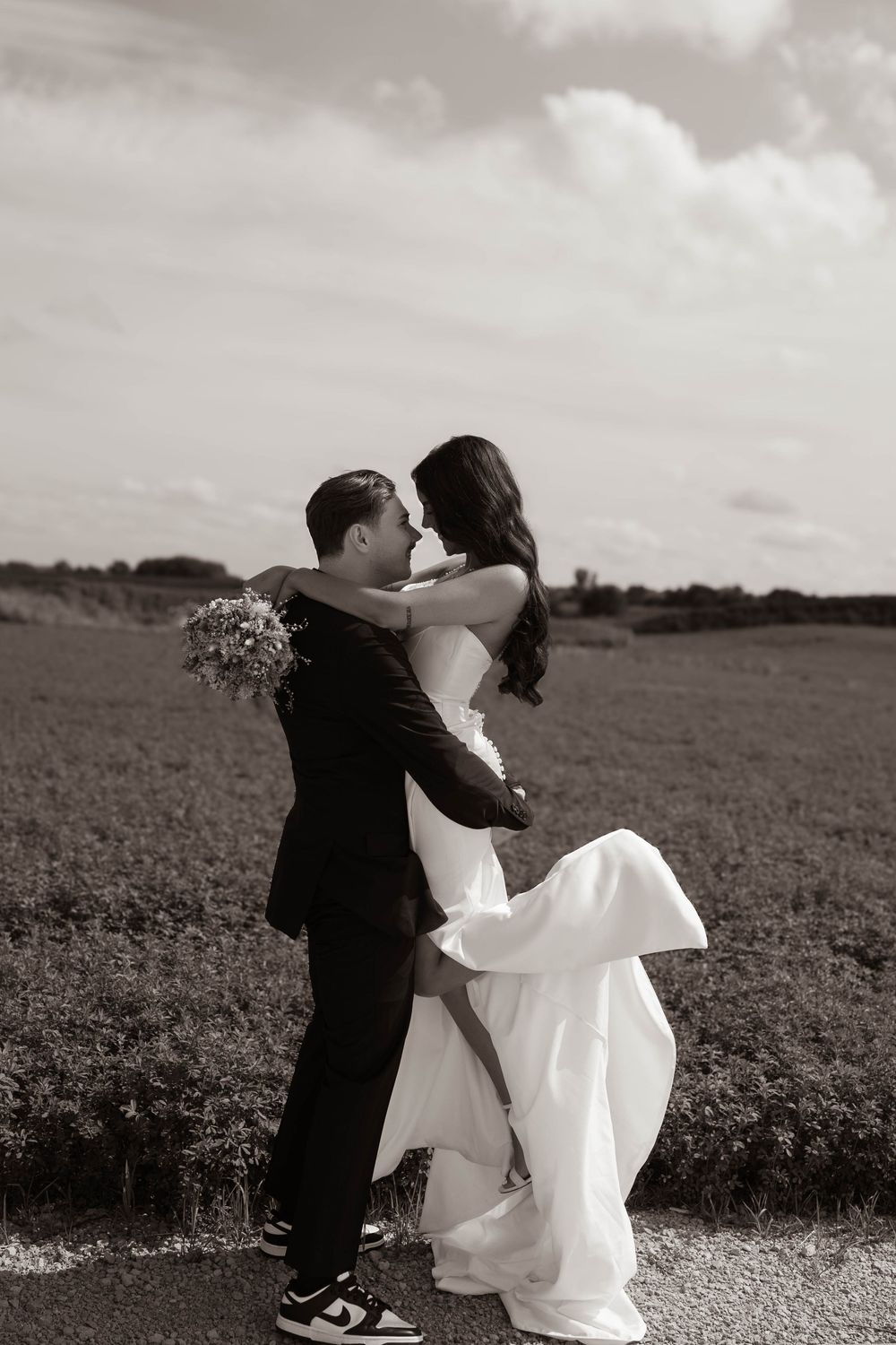 Black and white countryside wedding photos showing romantic moments in an open field.