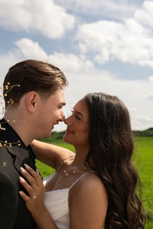 An intimate wedding portrait showing a couple's romantic moment in a sunny meadow.