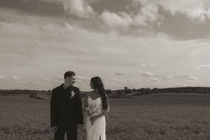 A dramatic black and white landscape wedding photo showing a couple against rolling hills.