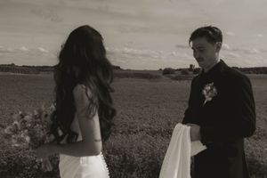 A black and white photo of newlyweds standing in an open field.