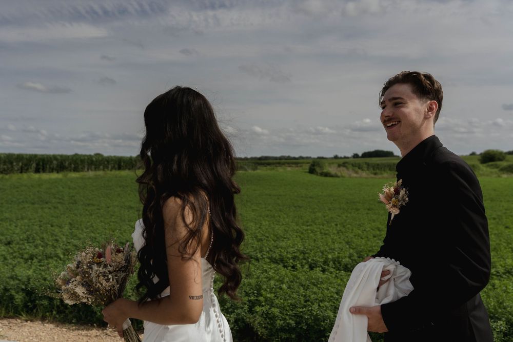 Candid wedding moment in countryside with dress train and natural scenery.