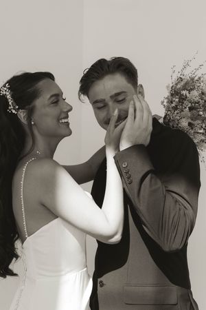 A black and white portrait of a couple sharing an intimate moment in wedding attire.