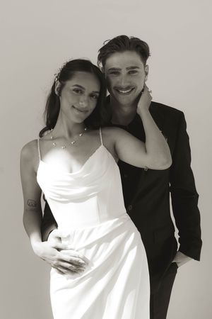 A romantic black and white studio portrait of a couple in formal wedding attire.