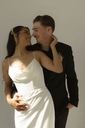 A sun-lit portrait of a couple in wedding attire sharing a joyful moment.