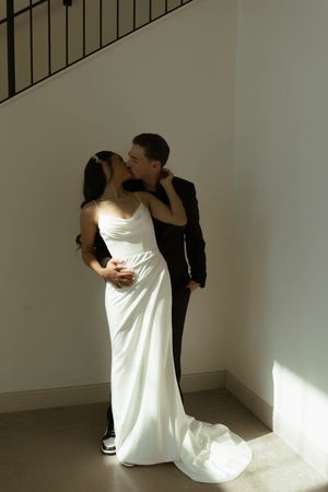 A tender moment between newlyweds near a staircase with dramatic lighting.