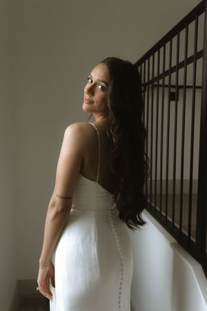 Bride in a white wedding dress poses gracefully against a staircase railing.