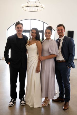 Wedding party poses together in formal attire in a bright modern venue.