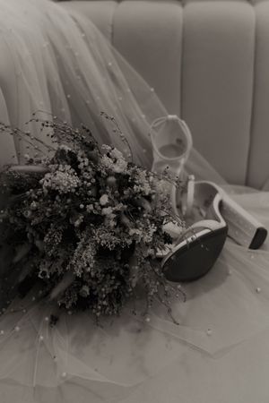 Black and white image of dried flowers and wedding dress details.