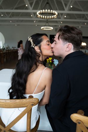 A romantic moment captured at a wedding reception with circular chandeliers overhead.