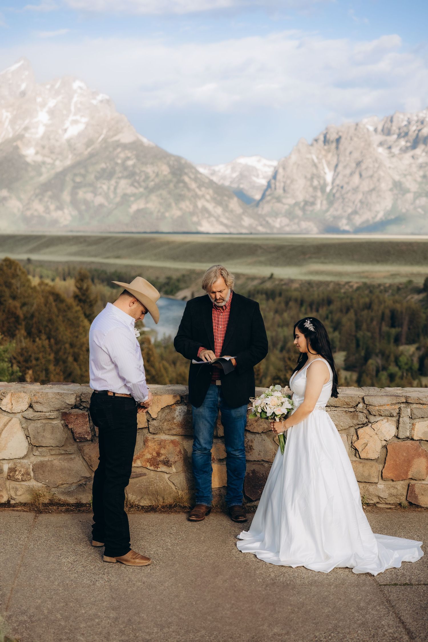 An intimate outdoor wedding ceremony takes place against the stunning backdrop of snow-capped Grand Teton mountains.