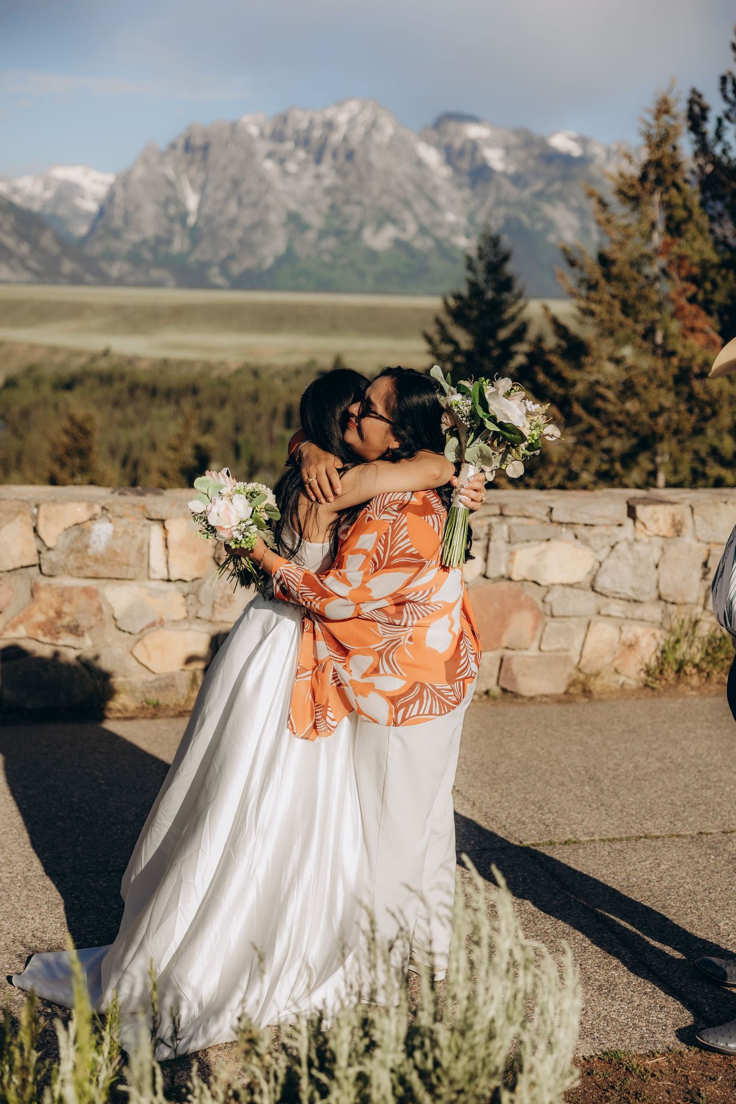 A newlywed couple embraces against a backdrop of snow-capped mountains in Grand Teton National Park.