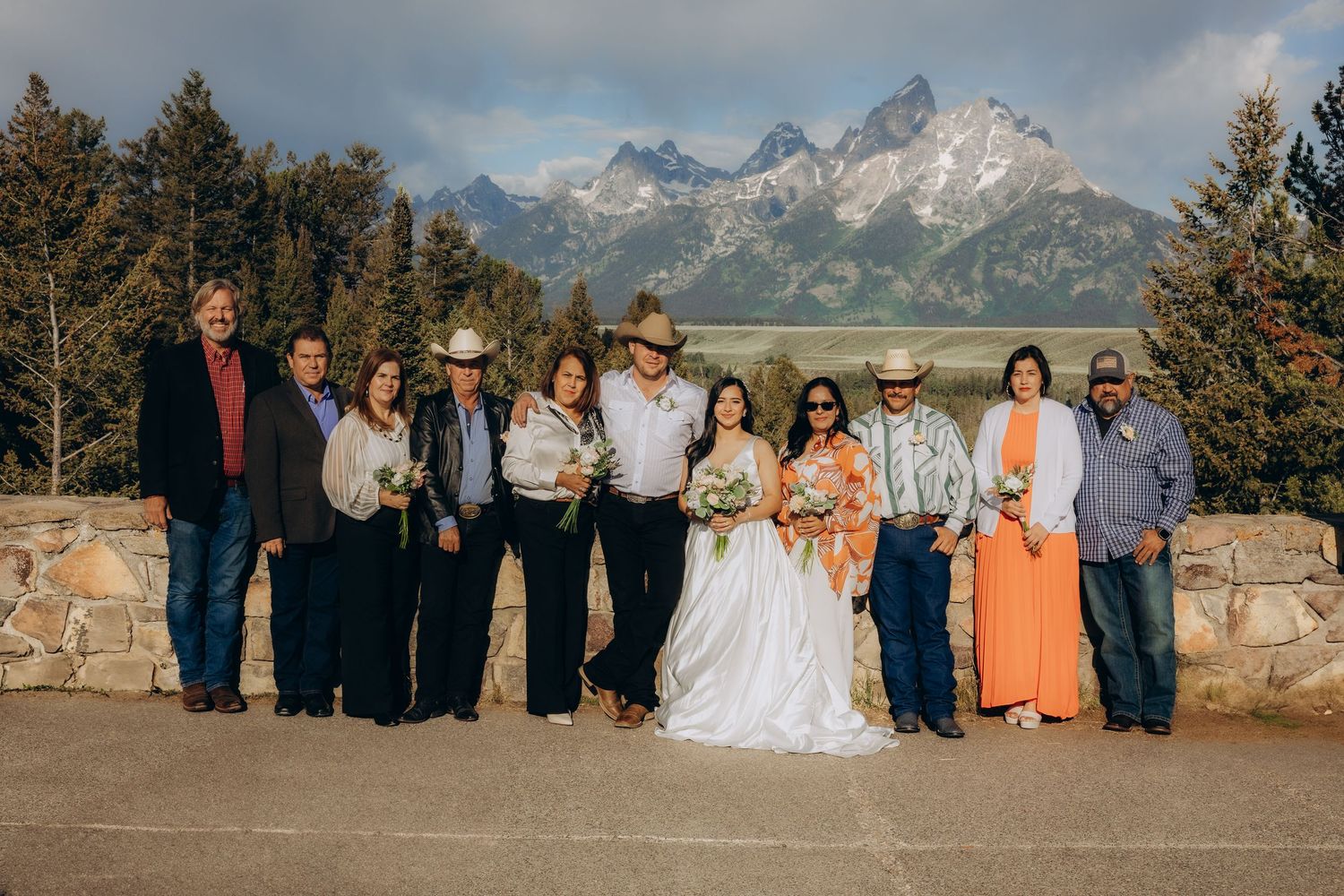 Wedding party group poses together against scenic mountain backdrop in Grand Teton National Park at sunset.