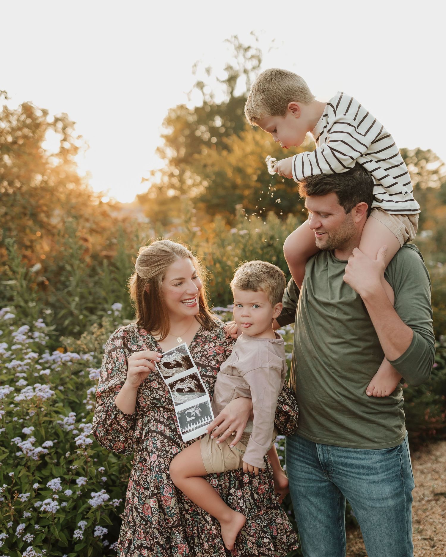 A family shares a joyful moment together in a field of wildflowers during golden hour sunset.