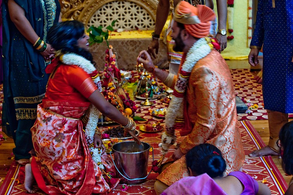 Traditional Sikh wedding ceremony with people in colorful attire performing rituals on a decorated red carpet.
