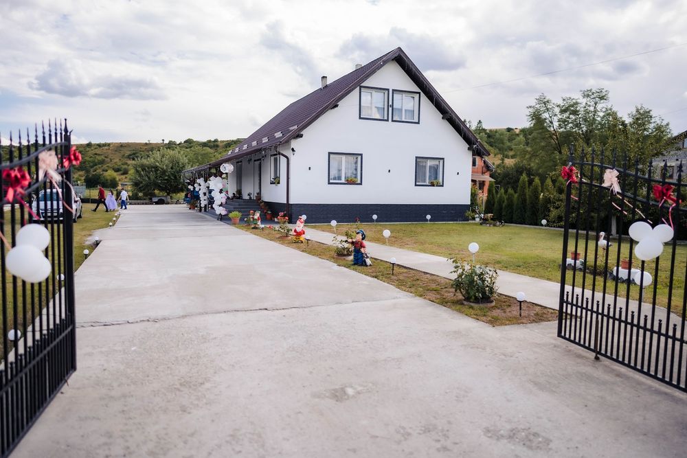 A panoramic view of a residential area with houses and paved driveways under a cloudy sky.