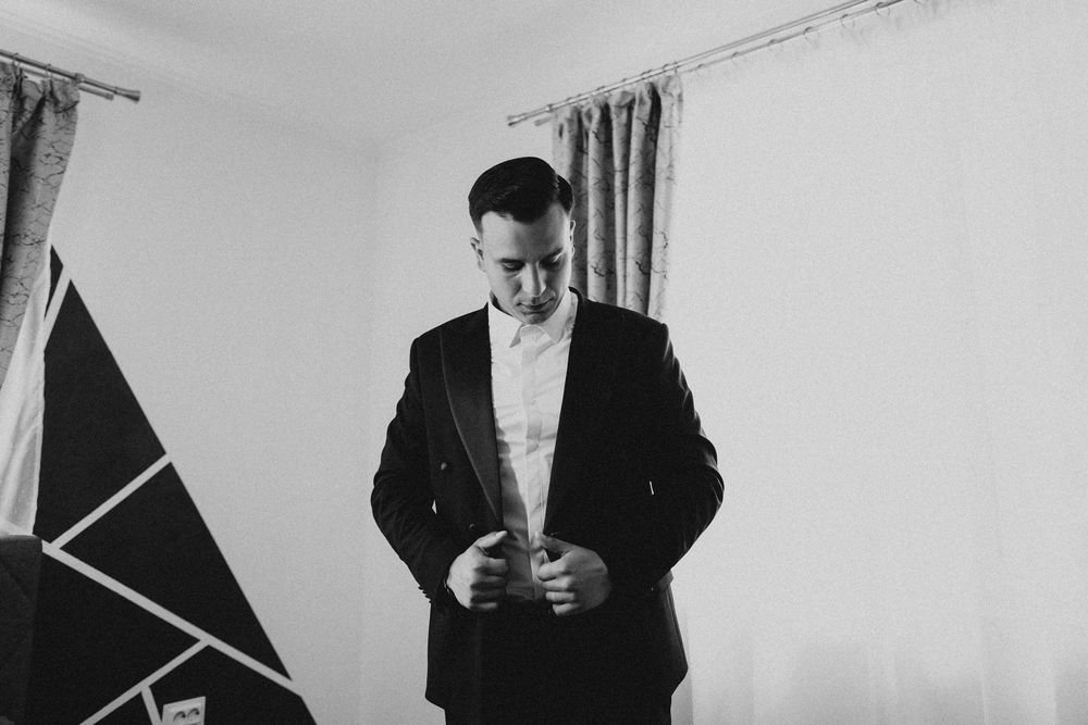 A sequence showing someone adjusting their formal attire in a bright room with decorative curtains.