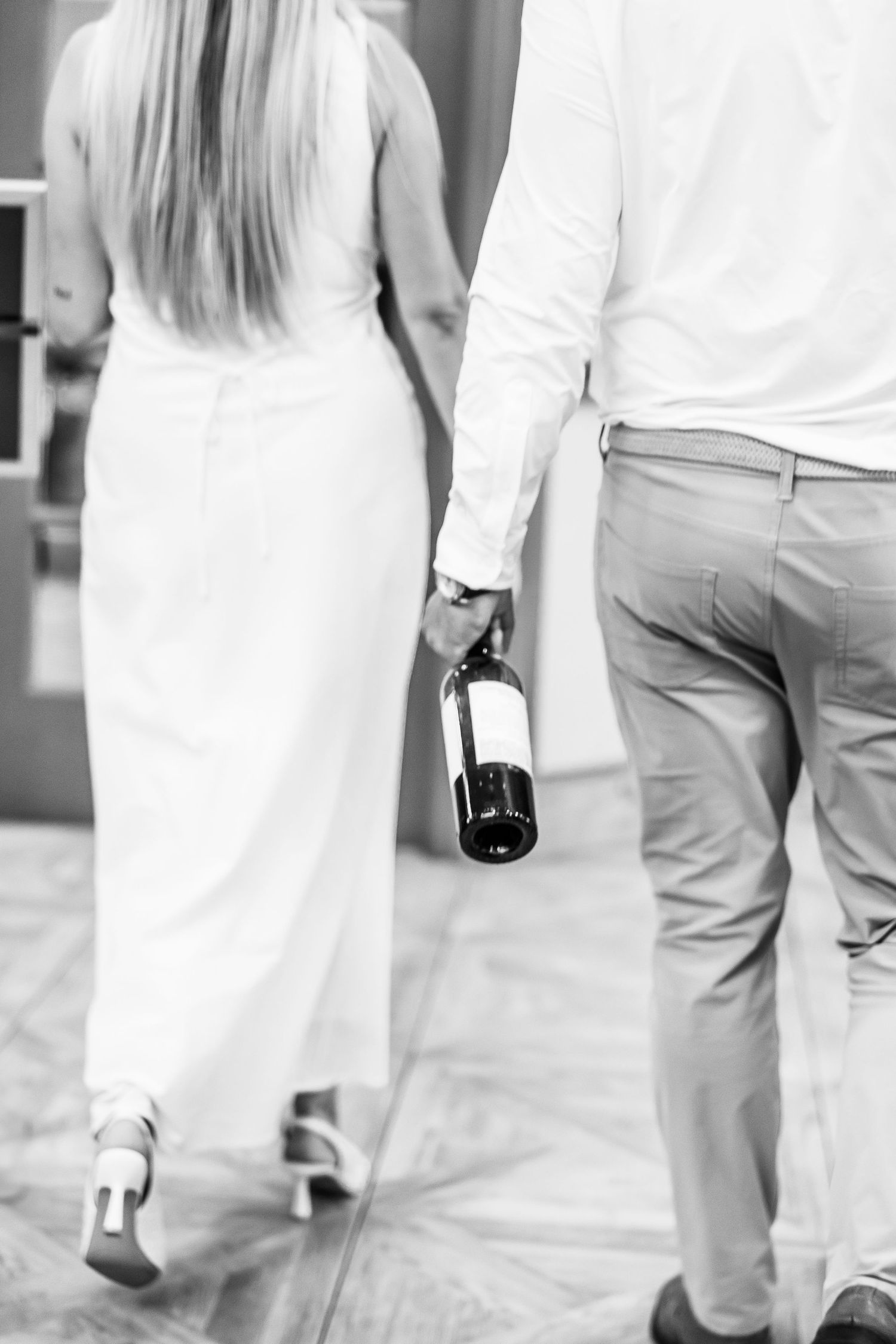 A series of black and white images showing people walking and holding wine bottles, wearing light colored clothing.