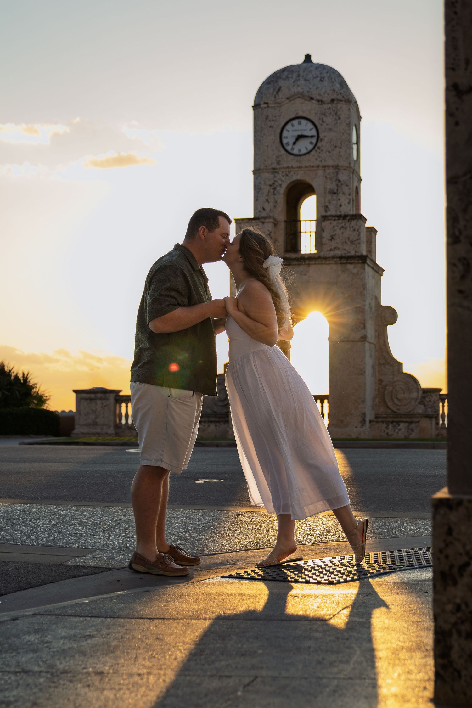 Romantic silhouettes embrace against sunset at historic clock tower.