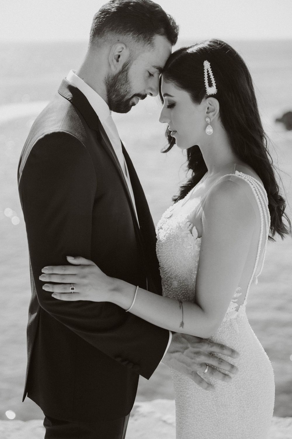 Intimate moment between couple in formal attire by the ocean.