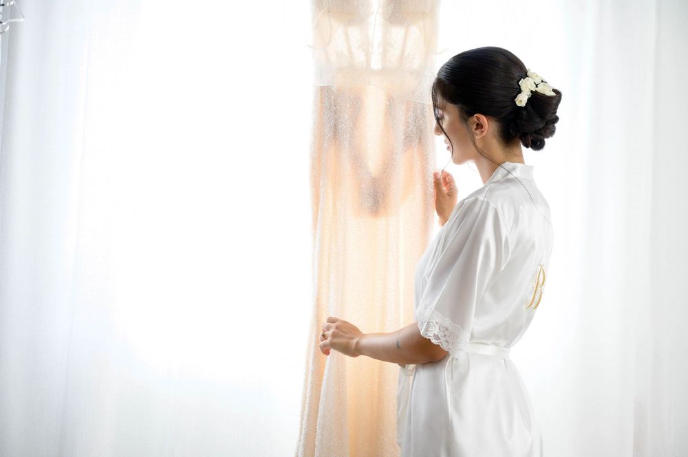 Silhouetted figure in white robe standing by window with soft morning light.