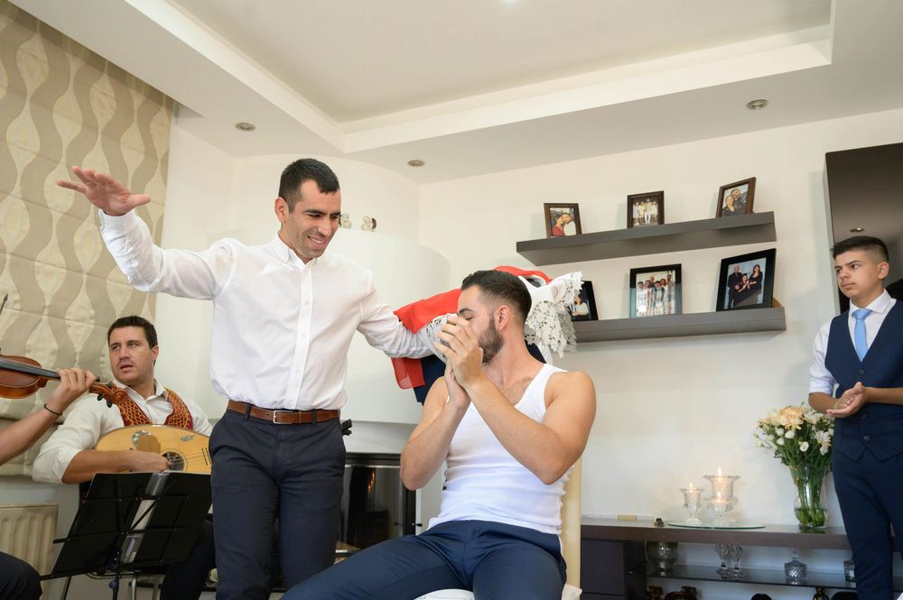 Groomsmen share a lighthearted moment while getting ready for a wedding with animated gestures and laughter.