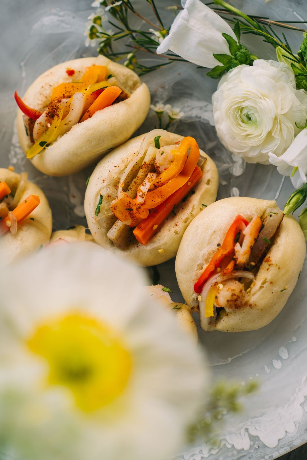 Elegant mini sandwiches with colorful vegetables garnished with white flowers.